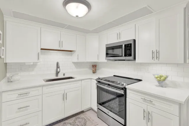 a kitchen with white cabinets stainless steel appliances and sink