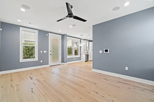 a view of an empty room with wooden floor and a window