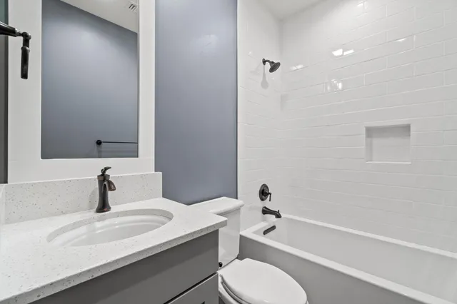 a bathroom with a granite countertop sink toilet a mirror and bathtub