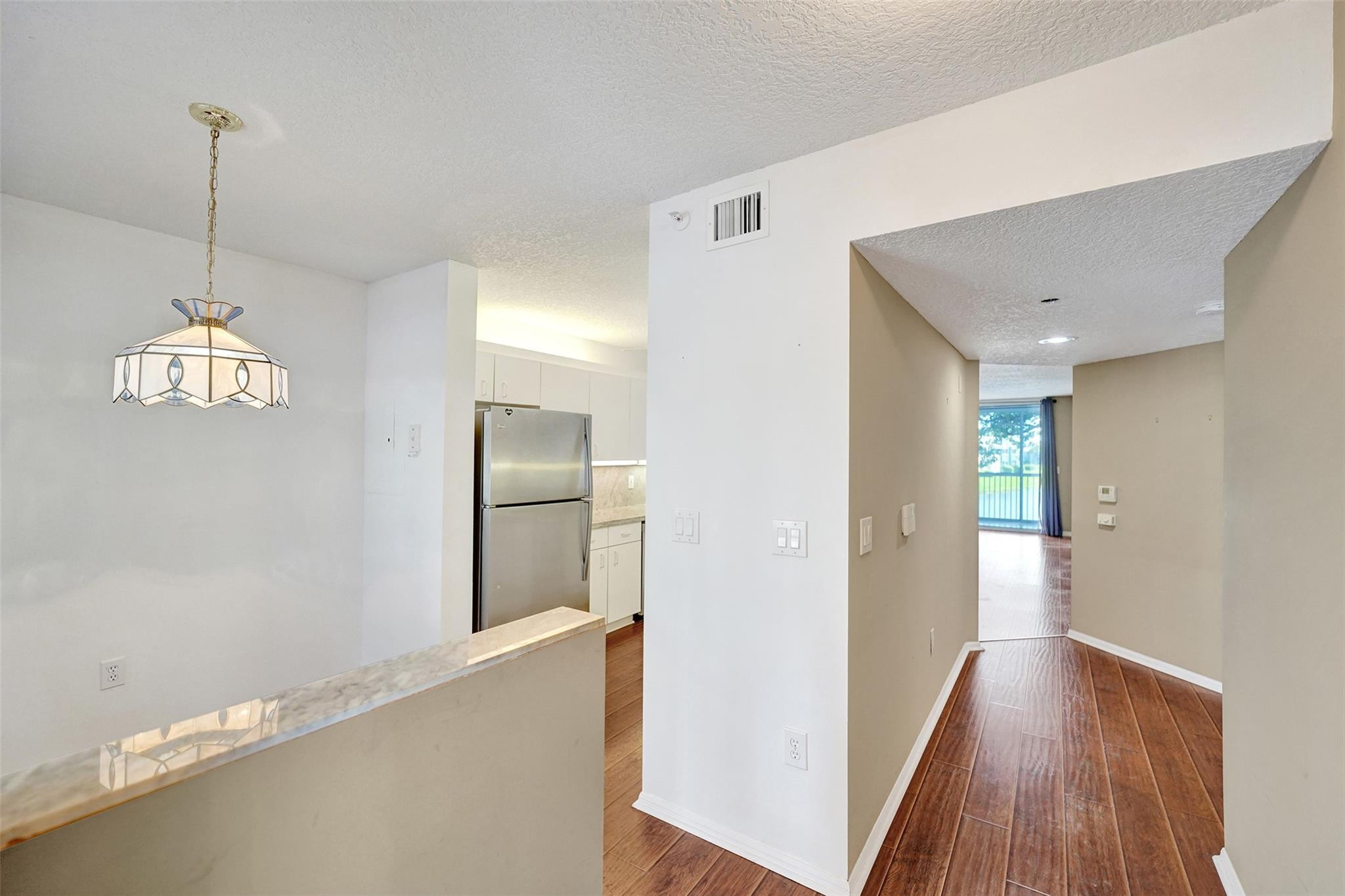 9563 Weldon Circle, Unit D212 Tamarac, FL 33321 - Photo 3 of 69 a view of a hallway with wooden floor and chandelier