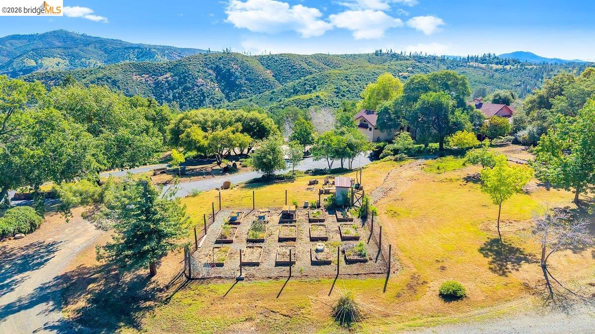 13700 Clements Road Groveland, CA 95321 - Photo 65 of 93 Fenced garden area featuring multiple raised beds, accompanied by natural landscaping and distant mountain scenery