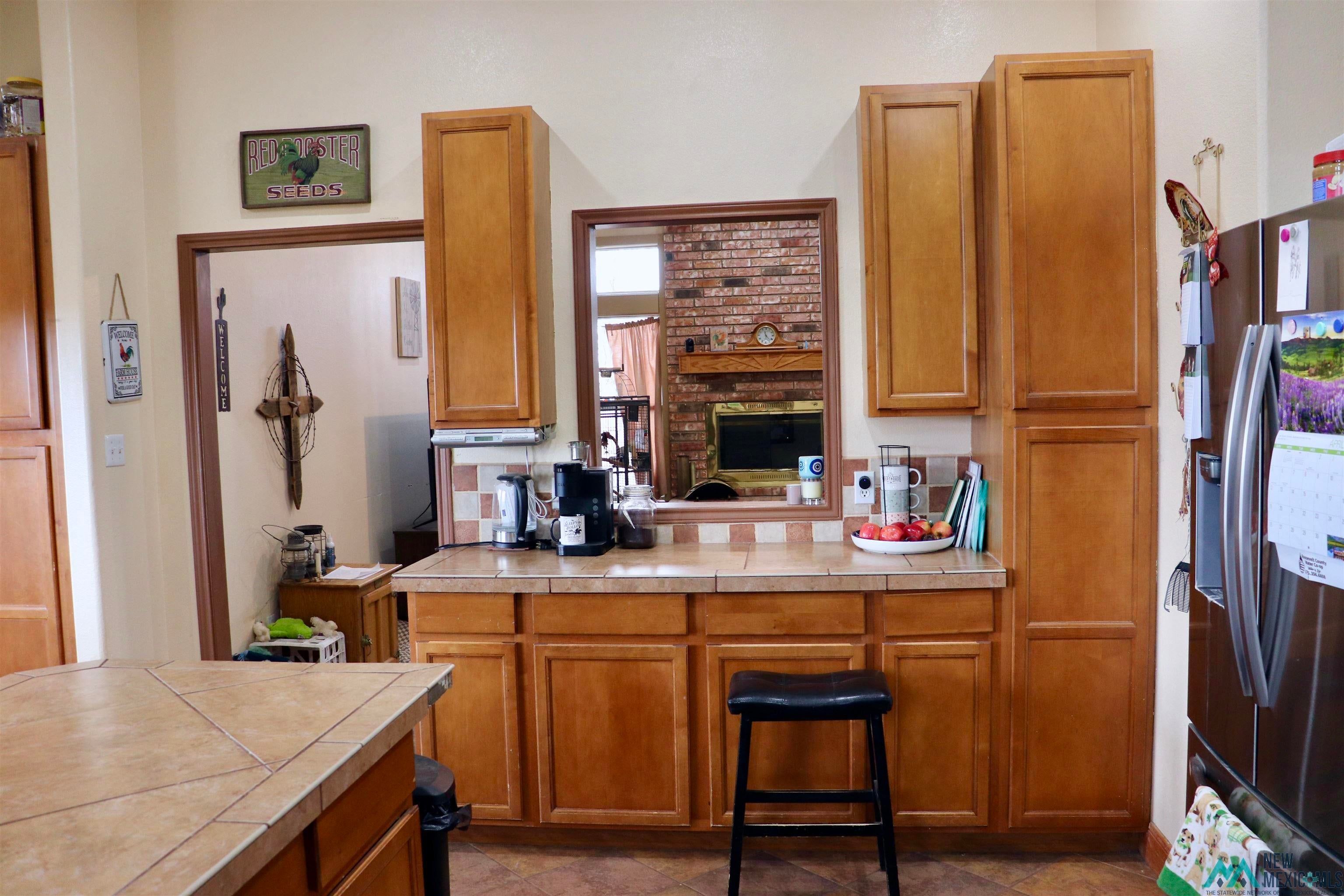 845 South Roosevelt Road South Portales, NM 88130 - Photo 14 of 47 Kitchen featuring stainless steel refrigerator with ice dispenser, tile countertops, and wood finish cabinetry