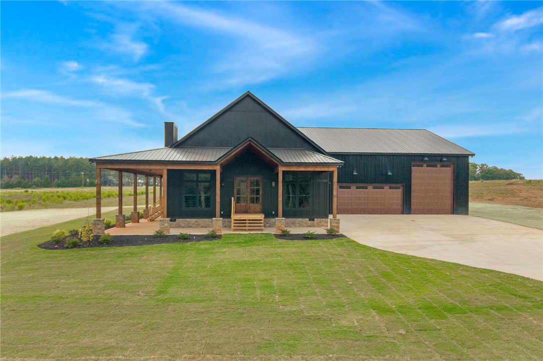 384 Jim Smith Road Pendleton, SC 29670 - Photo 1 of 48 A striking modern exterior features dark siding, stone accents, and a expansive wrap-around porch.