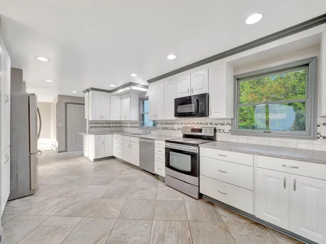 a kitchen with white cabinets and refrigerator