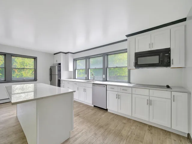 a large kitchen with stainless steel appliances kitchen island a large counter top and floors