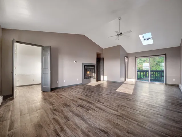 a view of an empty room with wooden floor and windows