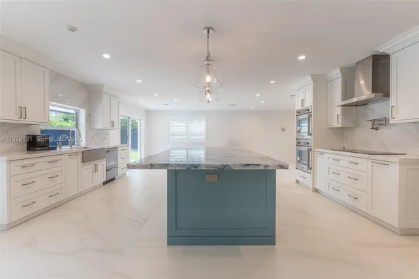 a kitchen with kitchen island granite countertop a white stove top oven and cabinets