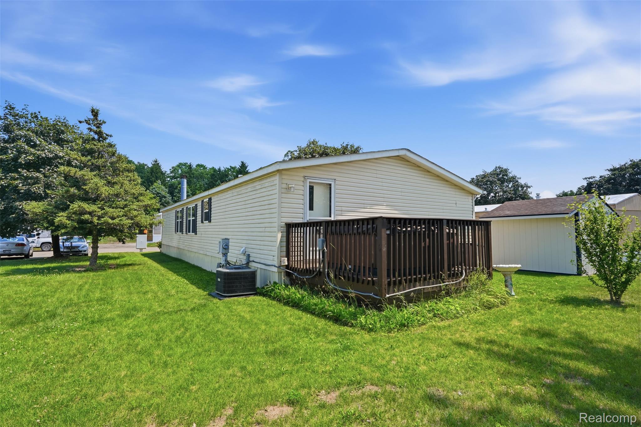 4634 Butternut Street Clarkston, MI 48348 - Photo 24 of 28 Cream-colored siding exterior featuring a dark wood deck and a detached storage shed