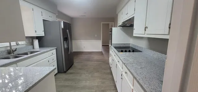 a kitchen with granite countertop a sink stove and refrigerator