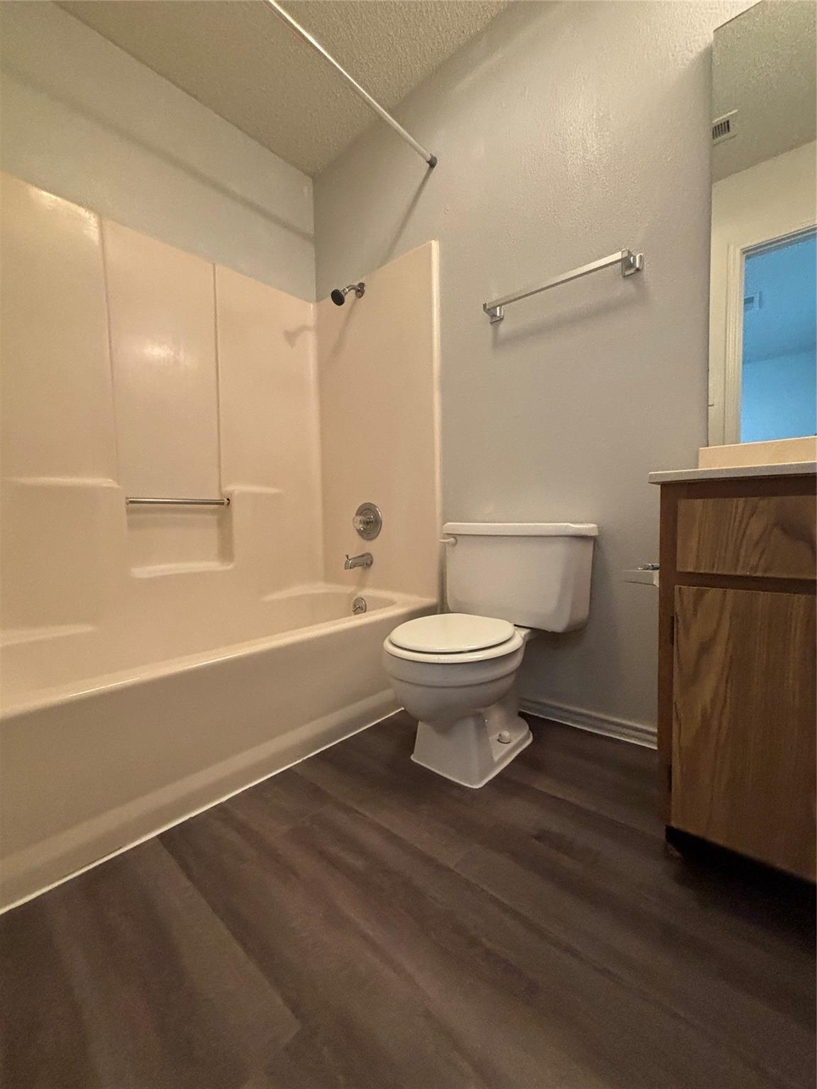 2033 Redwing Way Round Rock, TX 78664 - Photo 6 of 13 Bathroom featuring a white tub/shower combination, dark wood-finish flooring, a white toilet, and a wood-finish vanity with an integrated sink
