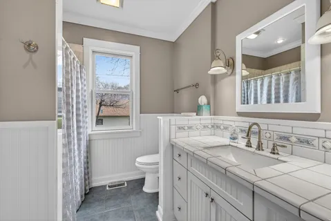 a bathroom with a granite countertop sink a toilet and a mirror
