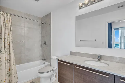a bathroom with a granite countertop sink a toilet a mirror a bathtub and shower