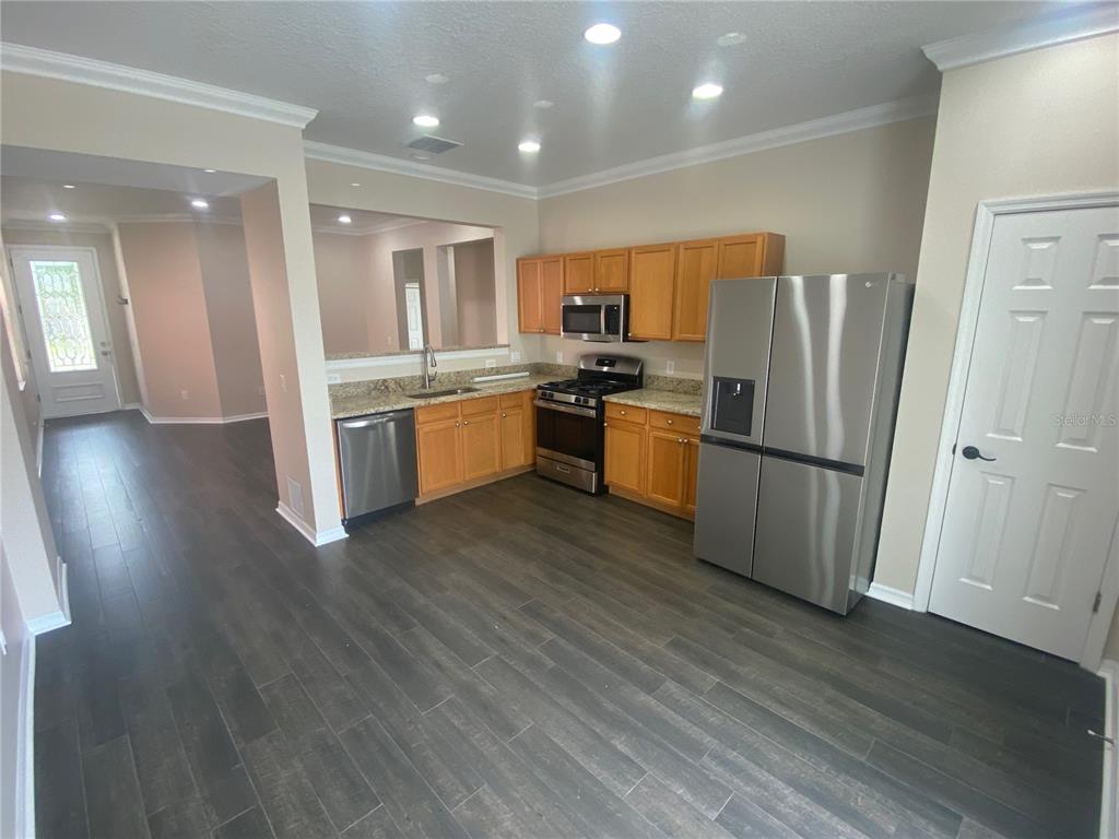2409 Spring Hollow Loop Wesley Chapel, FL 33544 - Photo 8 of 47 a kitchen with stainless steel appliances granite countertop a refrigerator a sink dishwasher a stove with wooden floors