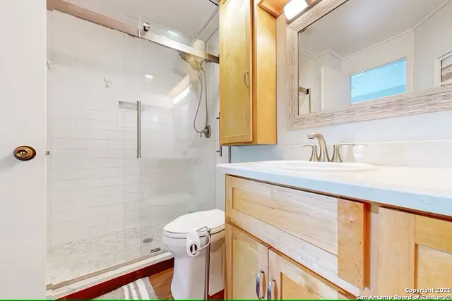 a bathroom with a sink a toilet a mirror and shower