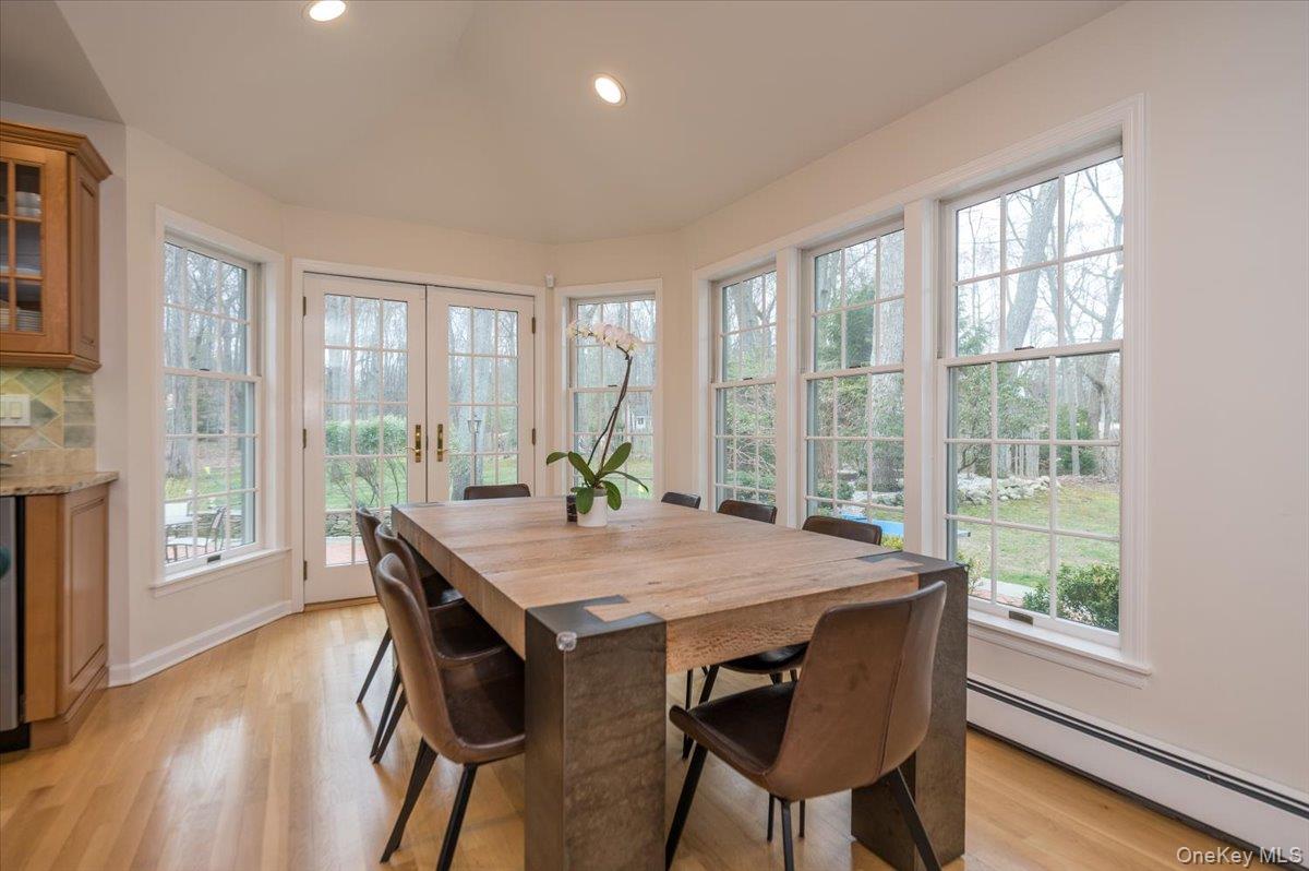 4 Springwood Path Syosset, NY 11791 - Photo 14 of 47 This dining area features hardwood floors and extensive windows, including double French doors, providing abundant natural light and views of the outdoors