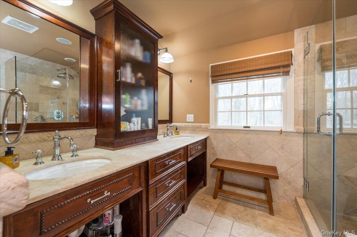 4 Springwood Path Syosset, NY 11791 - Photo 25 of 47 Bathroom featuring a dual vanity with richly stained wood cabinetry, light-colored stone countertops, chrome fixtures and plenty of storage.