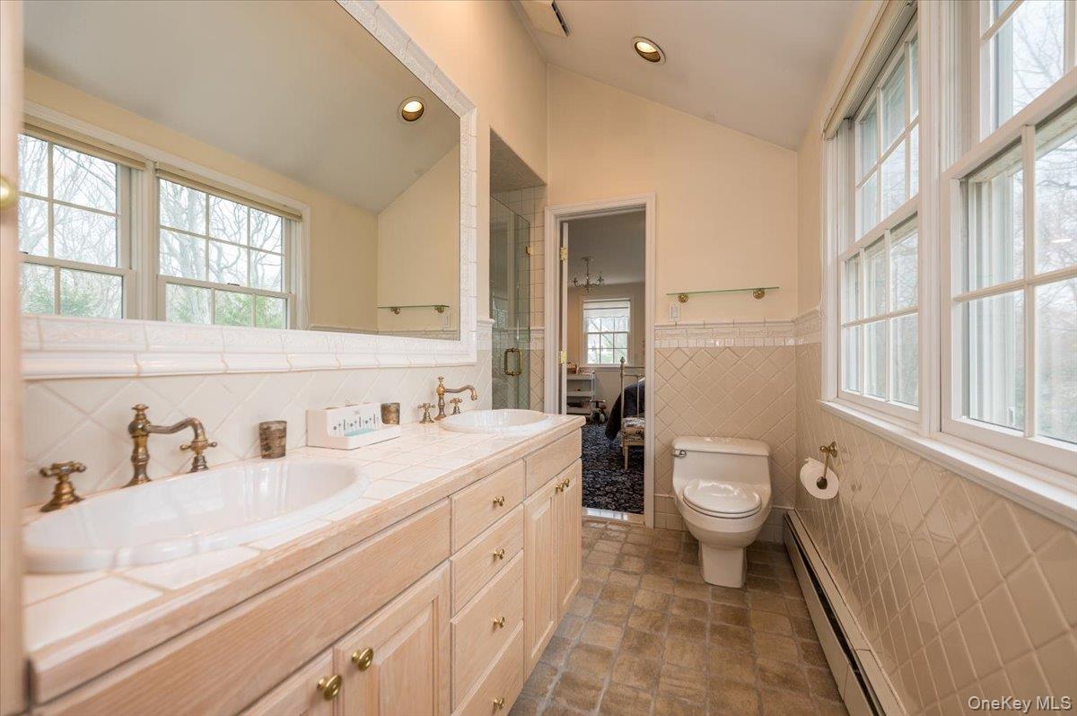 4 Springwood Path Syosset, NY 11791 - Photo 29 of 47 Jack-and-jill bathroom with tile flooring and double wood vanity. Tile flooring and tile wainscoting with glass enclosed shower stall.