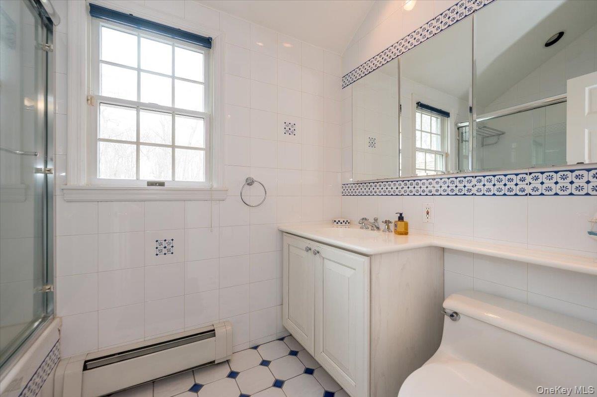 4 Springwood Path Syosset, NY 11791 - Photo 30 of 47 Full guest bathroom with decorative floor to ceiling tile, tile enclosed tub / shower combination with glass sliding door.