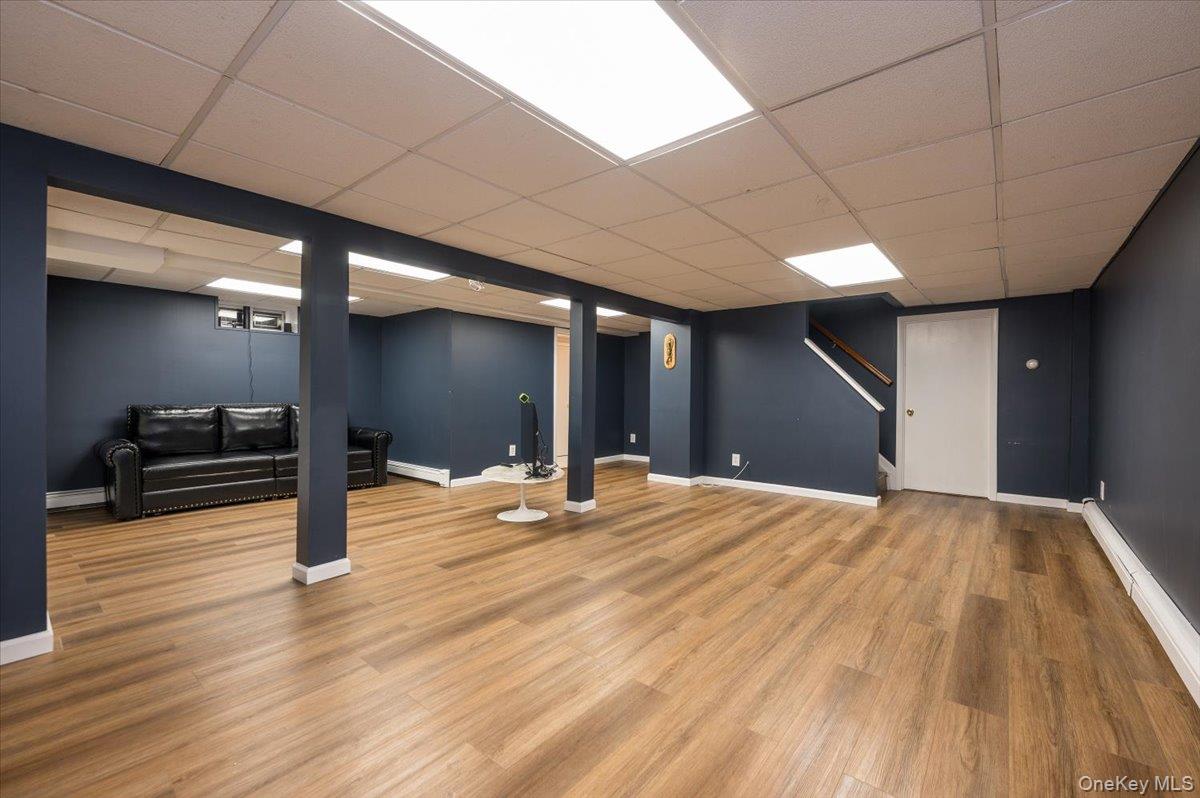 4 Springwood Path Syosset, NY 11791 - Photo 33 of 47 Spacious room with wood-style flooring, dark blue walls, white trim, and a drop ceiling with recessed lighting
