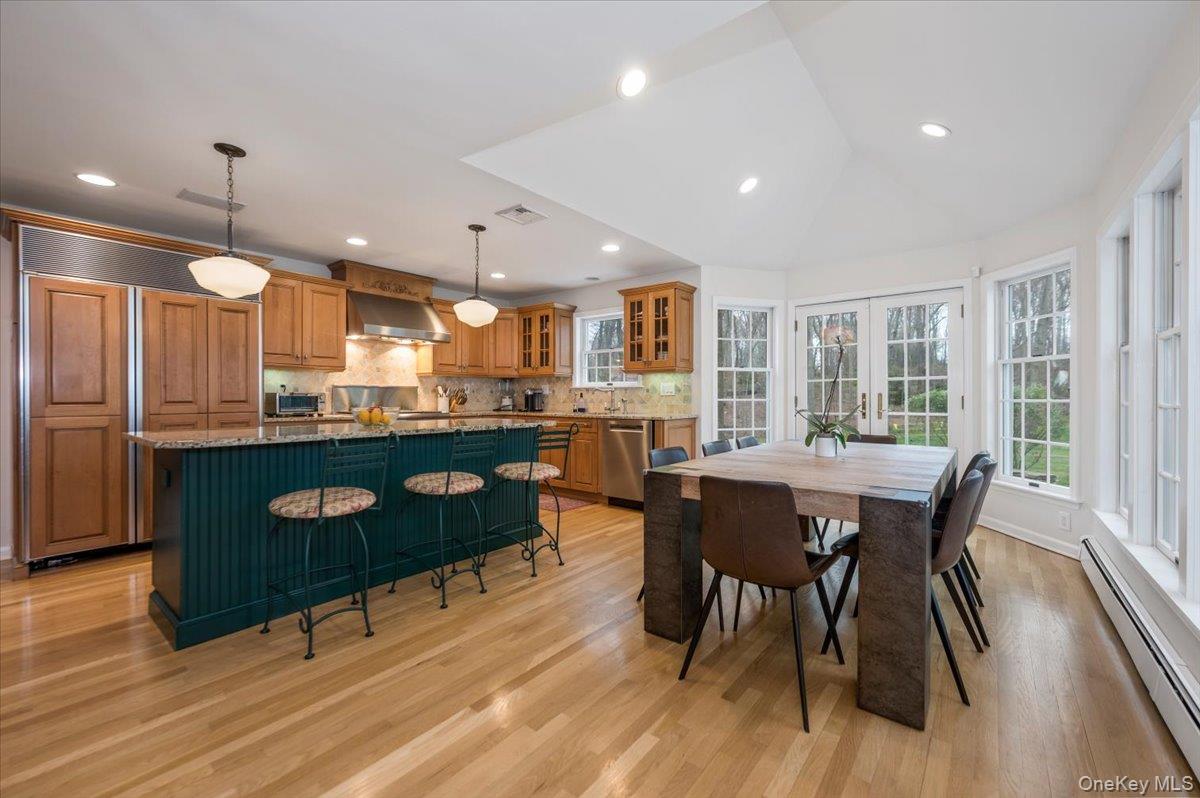 4 Springwood Path Syosset, NY 11791 - Photo 10 of 47 Beautiful eat-in kitchen with hardwood flooring, wood cabinetry and large island with stone countertops. Eating area with raised ceiling, wall of windows and french doors leading to patio and backyard.