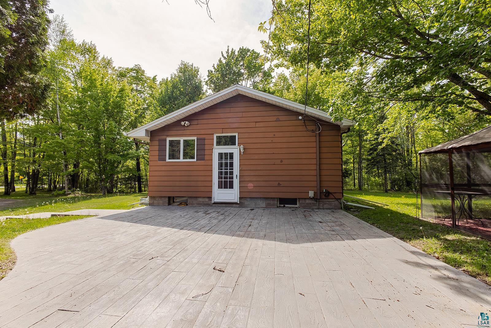 7045 Morris Thomas Road Cloquet, MN 55720 - Photo 3 of 28 Brown aluminum siding exterior with white trim details and a large stamped concrete patio