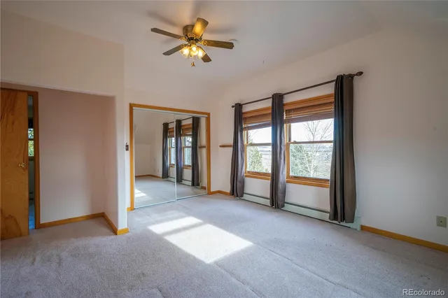 an empty room with chandelier fan and windows