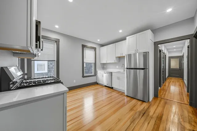 a kitchen with stainless steel appliances granite countertop a refrigerator a stove and a wooden floors