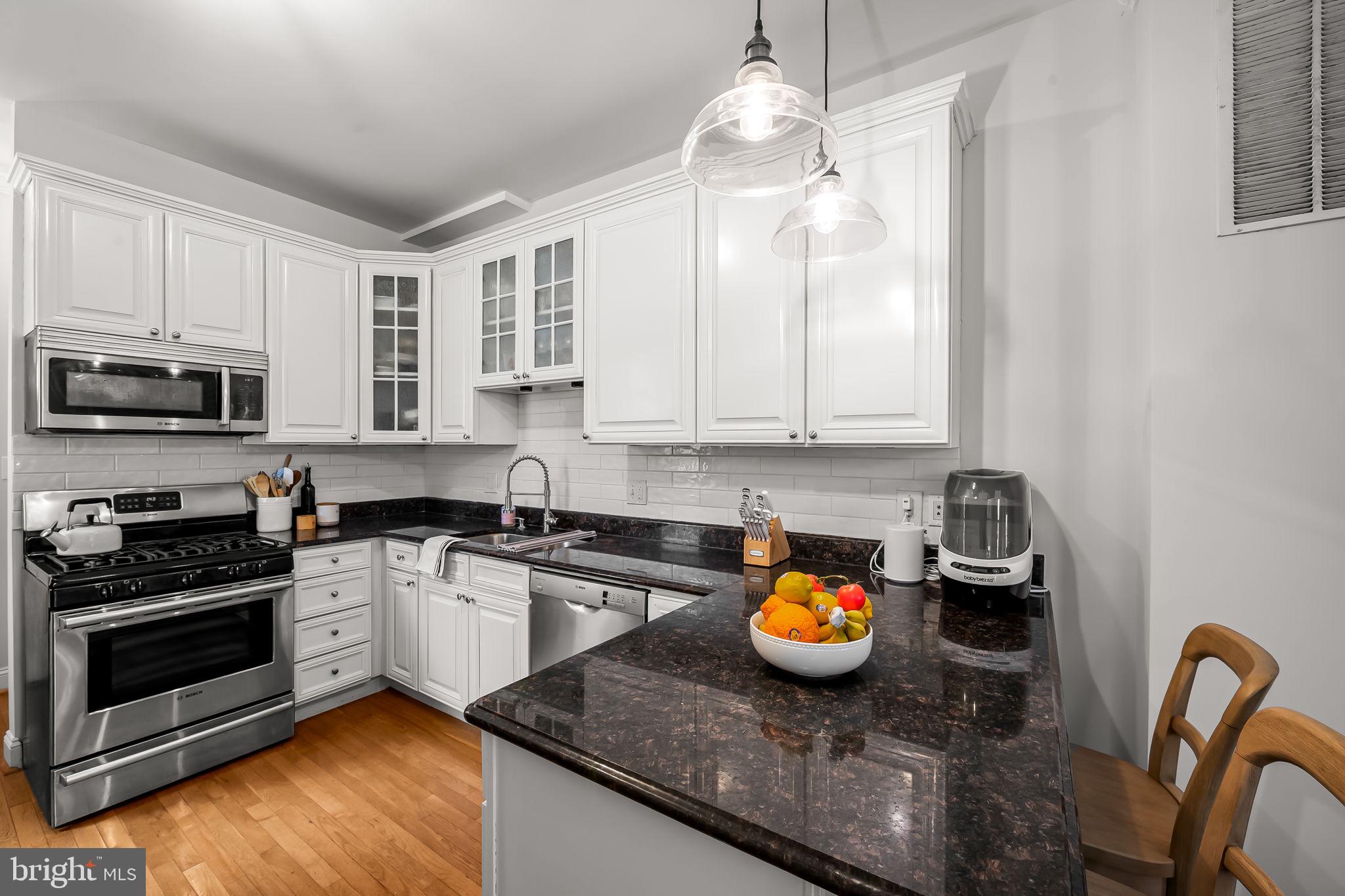 61 East Heath Street Baltimore, MD 21230 - Photo 12 of 30 a kitchen with stainless steel appliances granite countertop a stove a microwave a sink a stove and cabinets