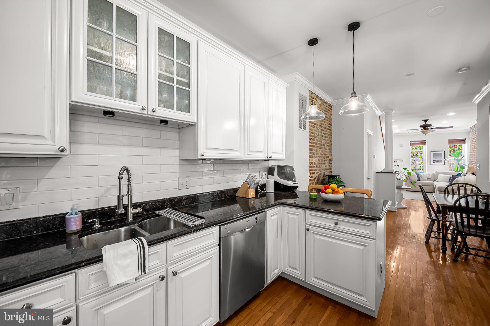 61 East Heath Street Baltimore, MD 21230 - Photo 15 of 30 a kitchen with stainless steel appliances a white wooden cabinets a sink a stove a dining table and chairs