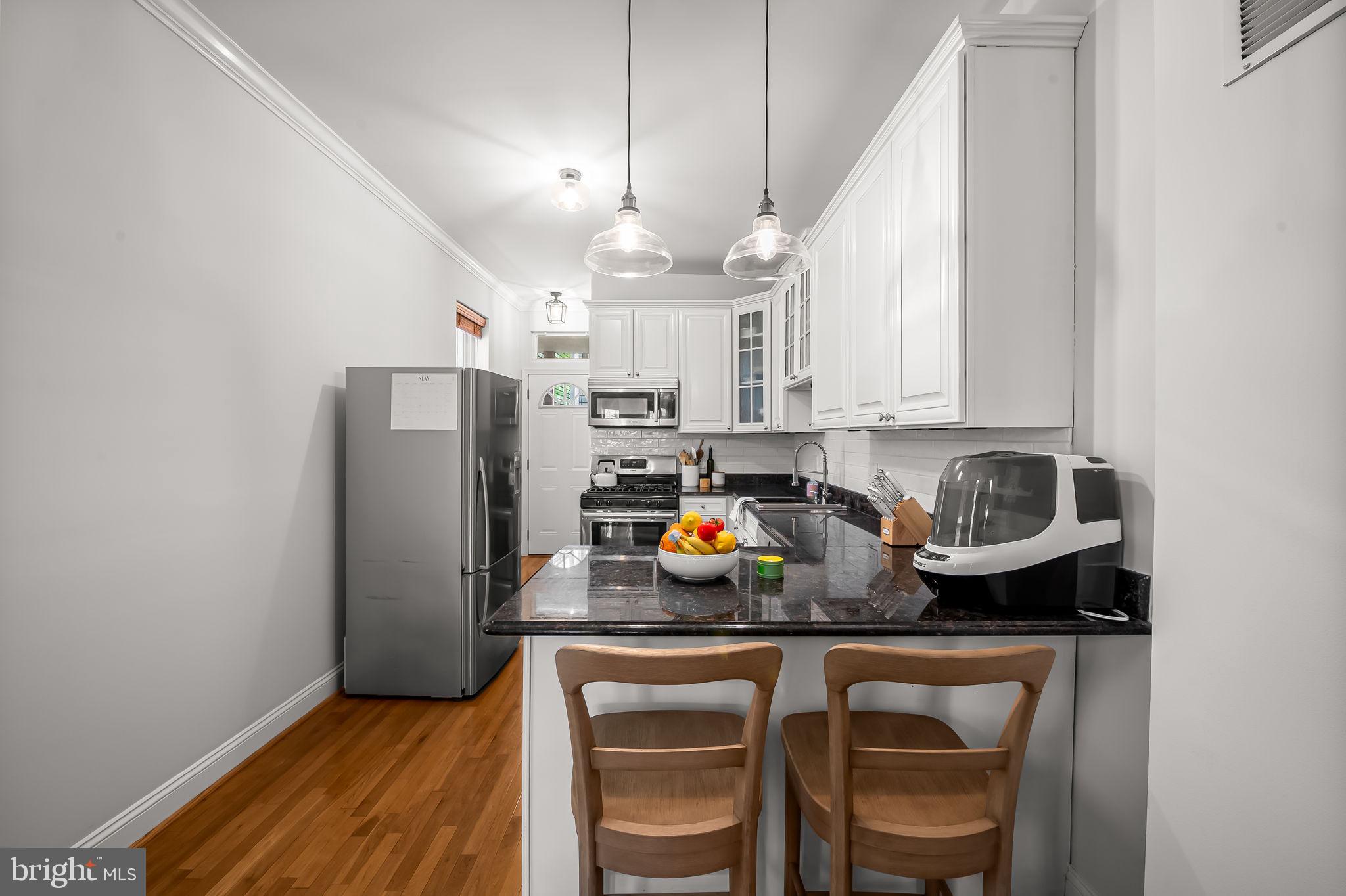 61 East Heath Street Baltimore, MD 21230 - Photo 10 of 30 a kitchen with stainless steel appliances granite countertop a refrigerator a sink dishwasher a dining table and chairs with wooden floor