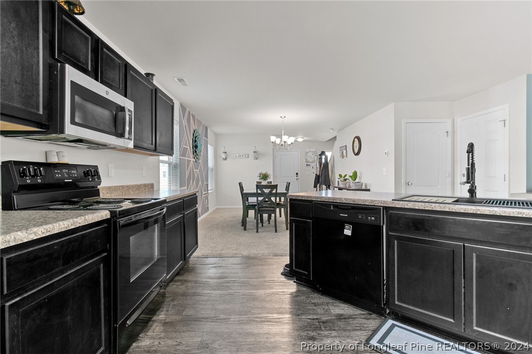 5942 Lowgrass Road Stedman, NC 28391 - Photo 3 of 28 a kitchen with stainless steel appliances granite countertop a stove a sink and a microwave