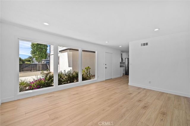 a view of an empty room with window and wooden floor