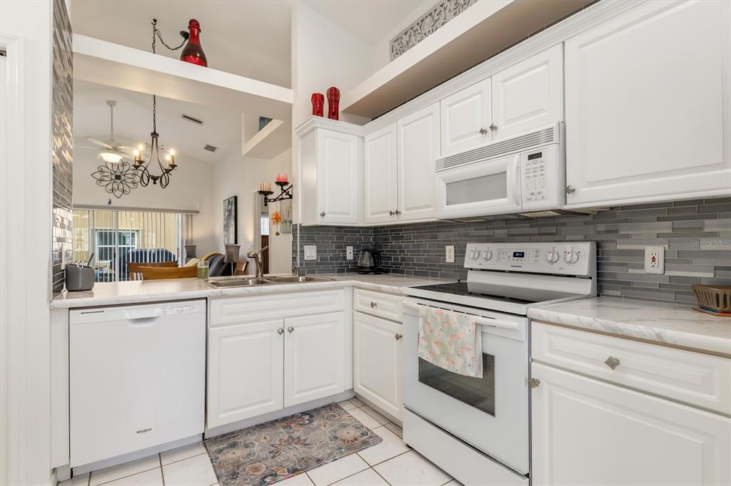 24167 Buckingham Way Punta Gorda, FL 33980 - Photo 12 of 42 a kitchen with white cabinets and white appliances