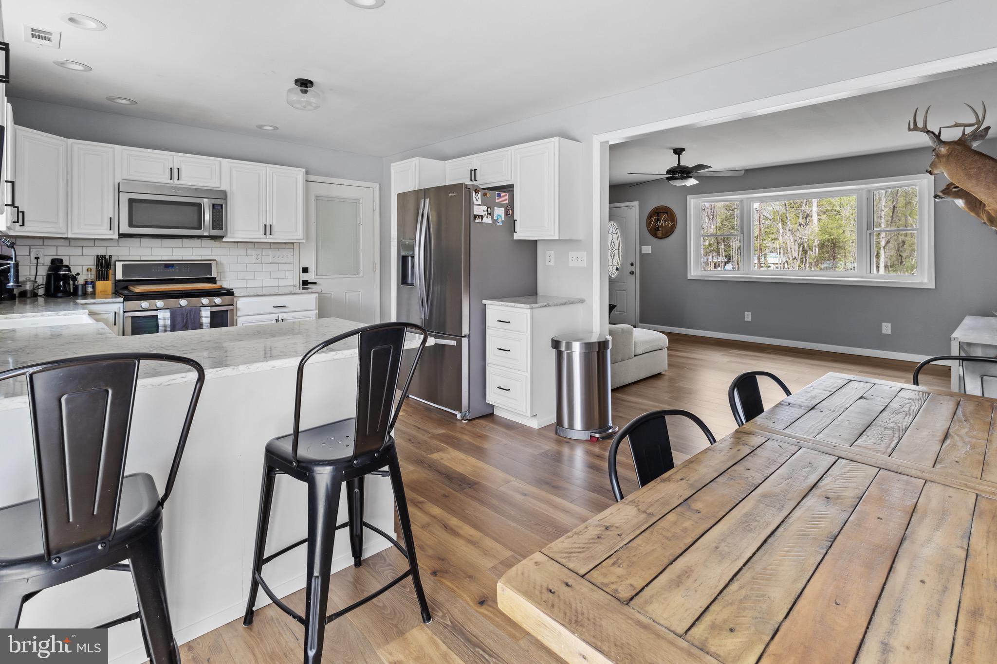 153 Crystal Road Elmer, NJ 08318 - Photo 6 of 29 a kitchen with stainless steel appliances a microwave a stove a sink dishwasher a dining table and chairs with wooden floor