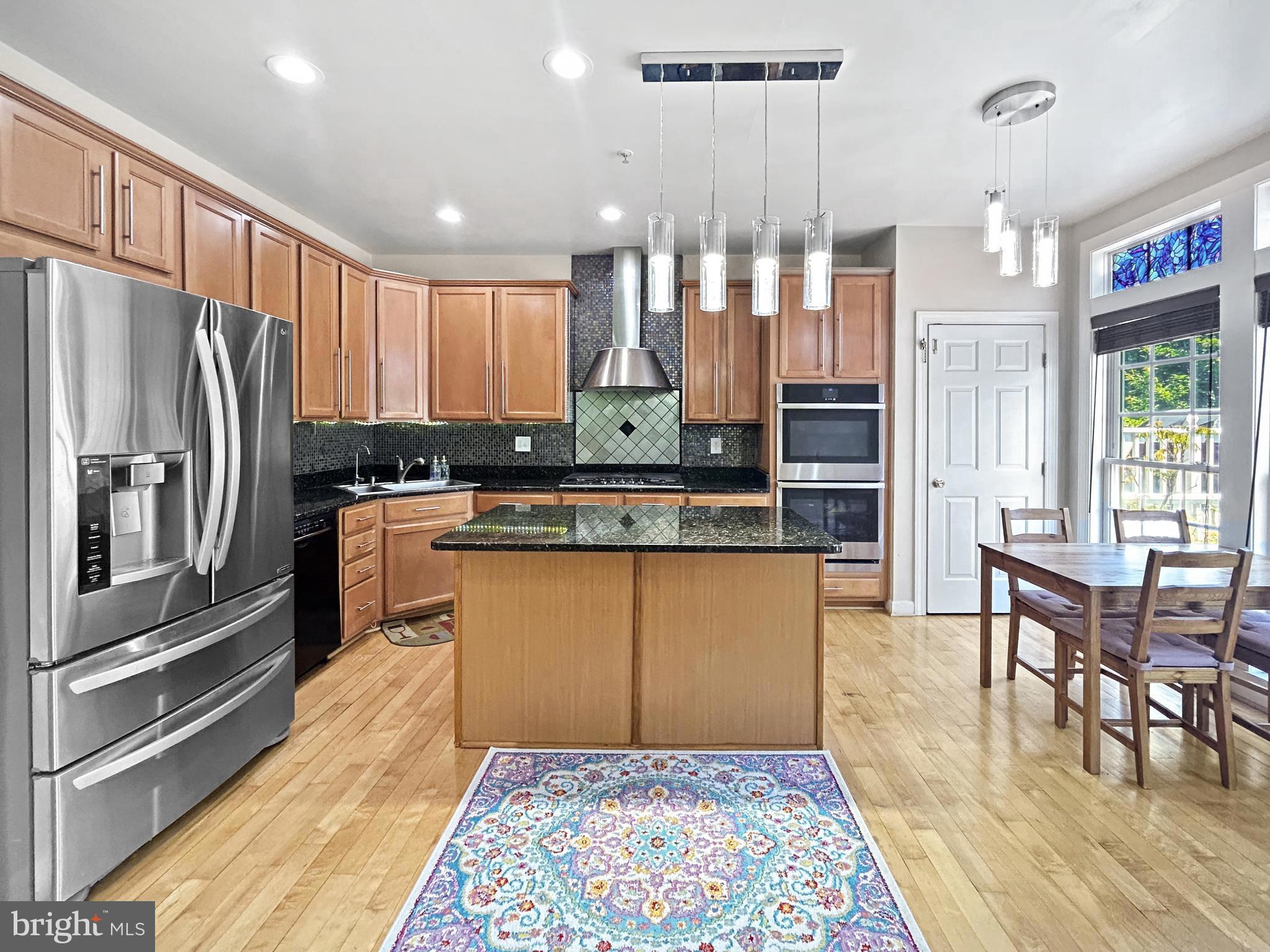 913 Highland Ridge Avenue Gaithersburg, MD 20878 - Photo 3 of 38 a kitchen with stainless steel appliances granite countertop a refrigerator a stove a sink a dining table and chairs with wooden floor