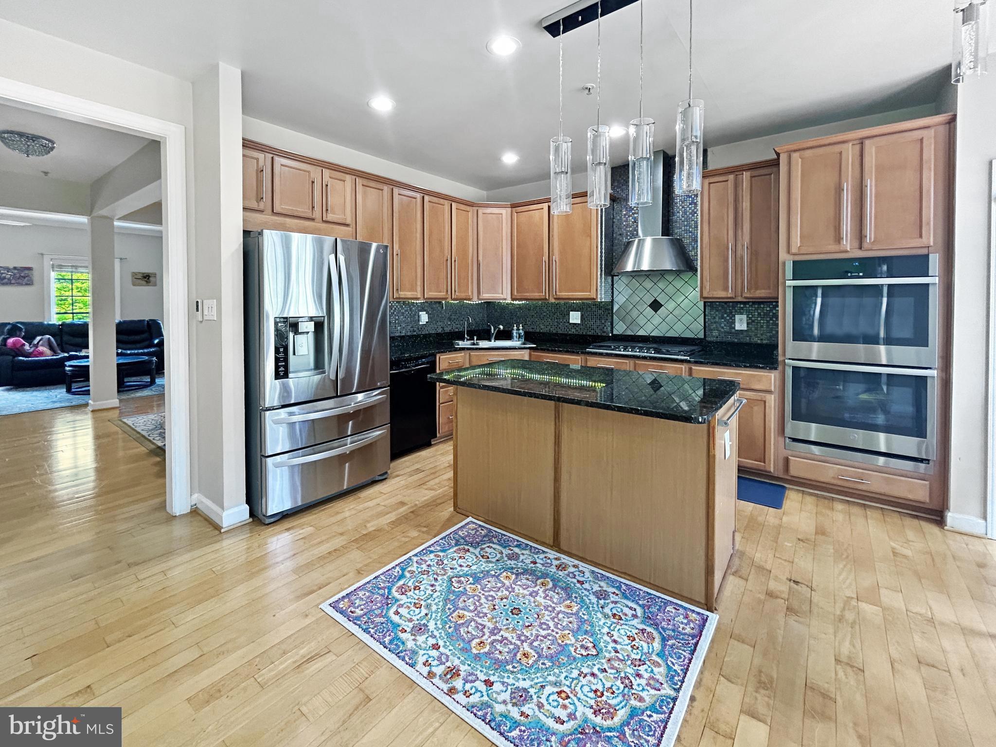 913 Highland Ridge Avenue Gaithersburg, MD 20878 - Photo 4 of 38 a kitchen with kitchen island granite countertop wooden cabinets a refrigerator and a sink