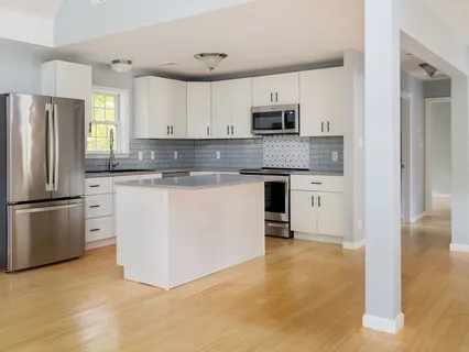a kitchen with stainless steel appliances granite countertop a stove top oven a refrigerator and white cabinets
