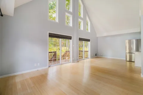 a view of an empty room with window and wooden floor