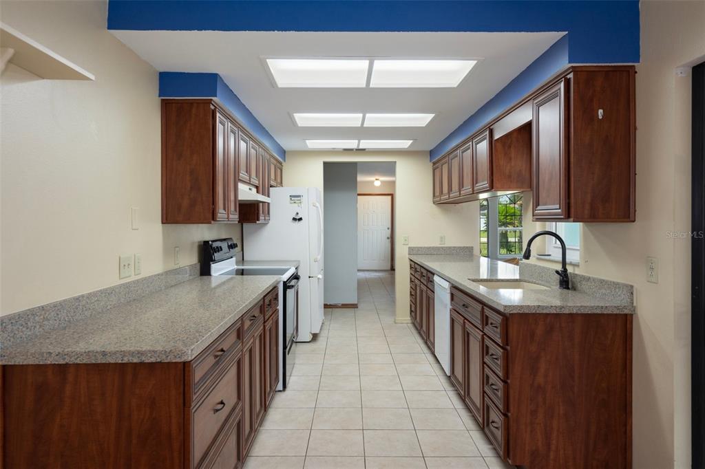 8332 Berkeley Manor Boulevard Spring Hill, FL 34606 - Photo 22 of 45 a kitchen with granite countertop a sink stove and cabinets