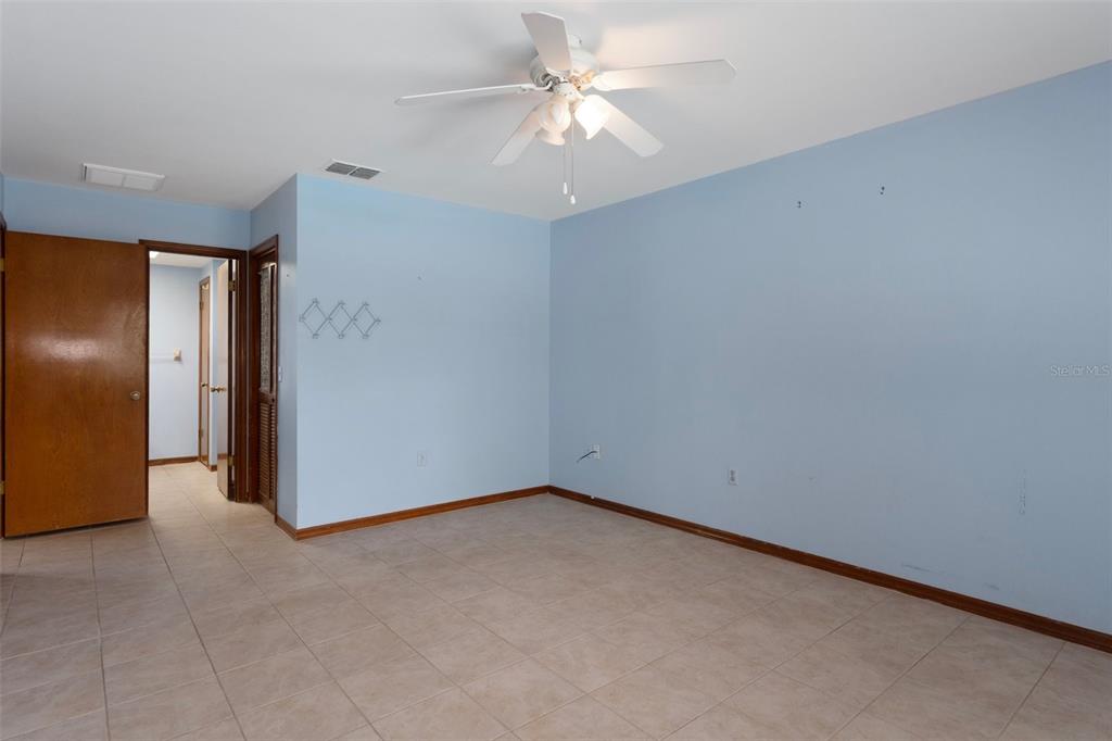 8332 Berkeley Manor Boulevard Spring Hill, FL 34606 - Photo 26 of 45 an empty room with a chandelier fan and windows