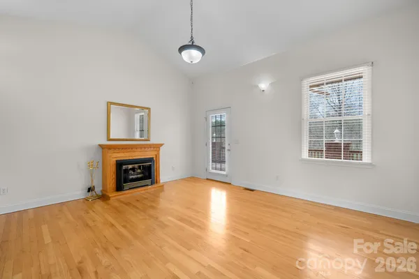 a view of empty room with a fireplace and wooden floor