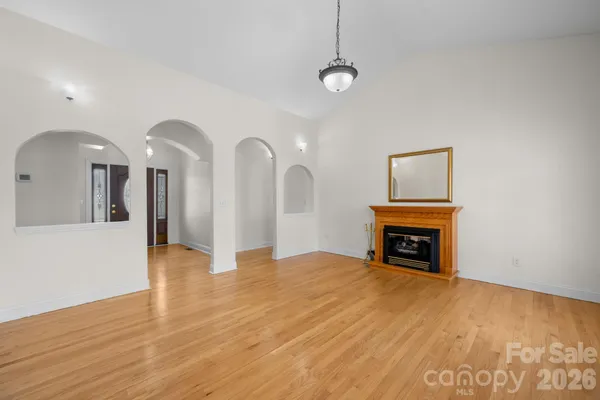 a view of an empty room with chandelier fan and wooden floor
