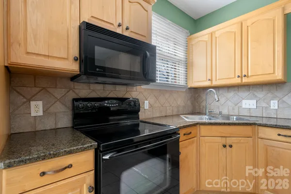 a kitchen with granite countertop white cabinets and black appliances