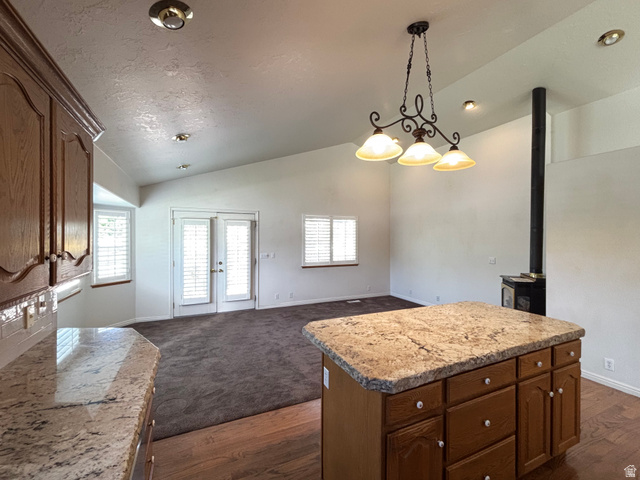 798 South 600 East Payson, UT 84651 - Photo 16 of 31 Kitchen island with granite countertop and wood cabinetry, open to a living area with vaulted ceilings, recessed lighting, and a wood-burning stove