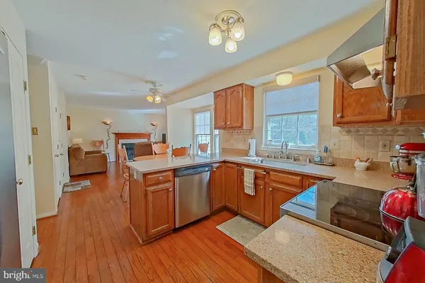 a large kitchen with stainless steel appliances granite countertop a stove refrigerator and a view of living room