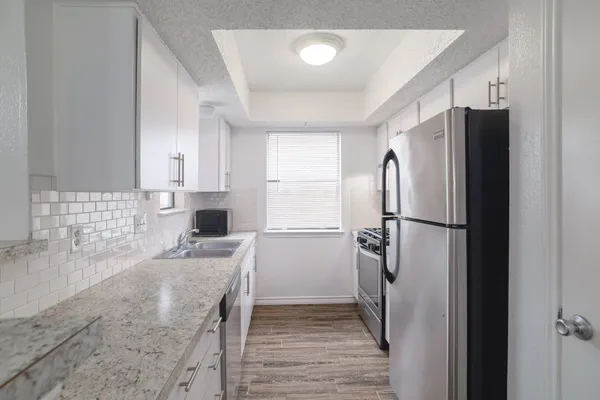 a kitchen with granite countertop a refrigerator and a sink