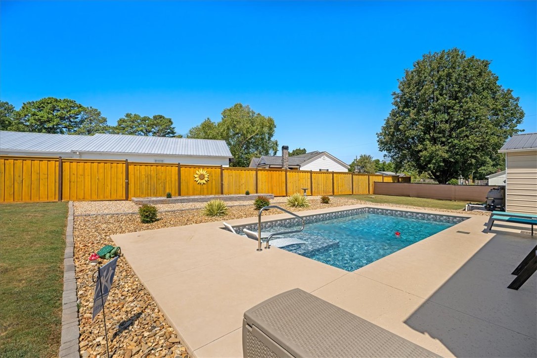 623 New Hope Road Anderson, SC 29626 - Photo 42 of 49 A sparkling in-ground pool is bordered by a concrete patio and a wooden privacy fence.