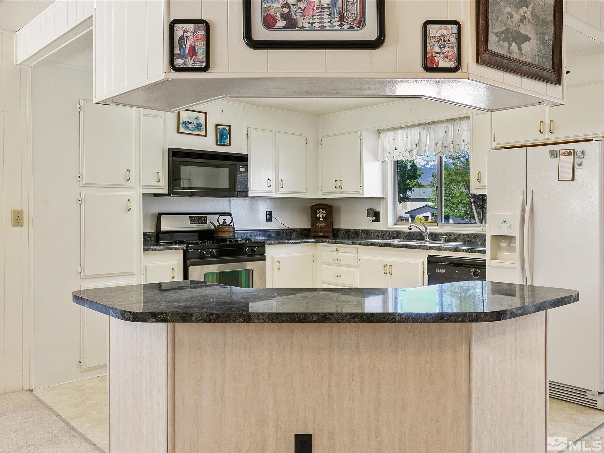 15010 Vega Street Reno, NV 89521 - Photo 12 of 30 a kitchen with stainless steel appliances granite countertop a sink a microwave a refrigerator and white cabinets
