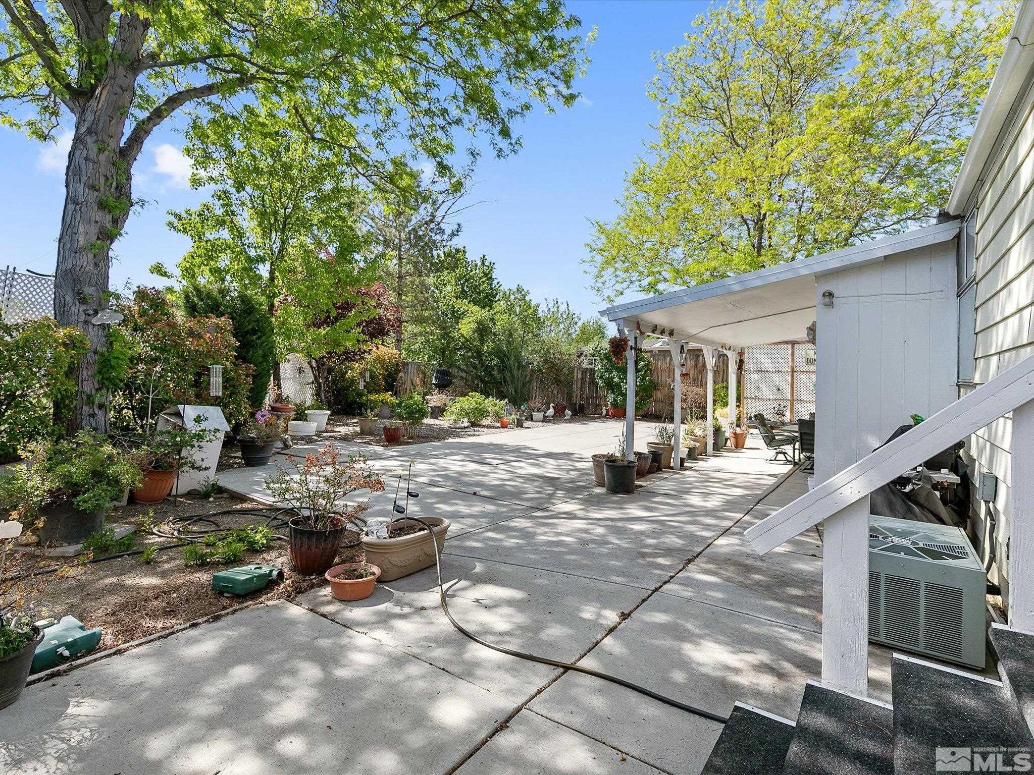 15010 Vega Street Reno, NV 89521 - Photo 27 of 30 a view of a patio with table and chairs under an umbrella with large trees