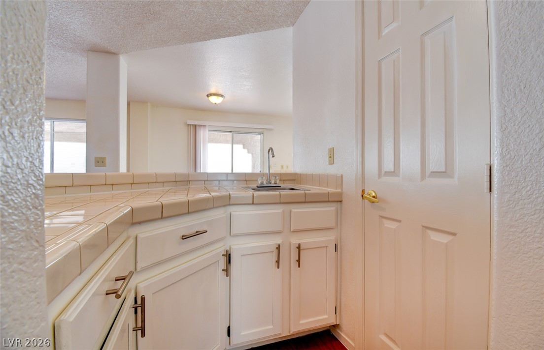 5 Tarryall Terrace Henderson, NV 89074 - Photo 12 of 44 A well-appointed wet bar with a tiled countertop and crisp white cabinetry stands ready for entertaining.